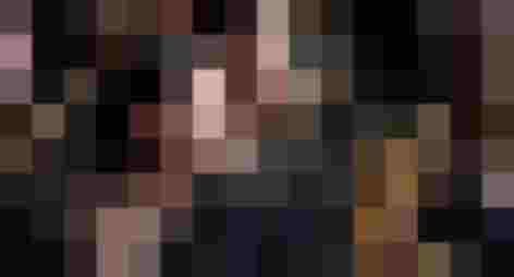 Musikerinnen spielen Blasinstrumente in einem Blasorchester, im Hintergrund weitere Musiker.