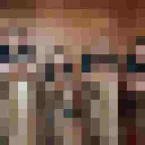 Vier Musiker posieren mit Tuben und Kontrabass vor einer Holzpaneelwand.