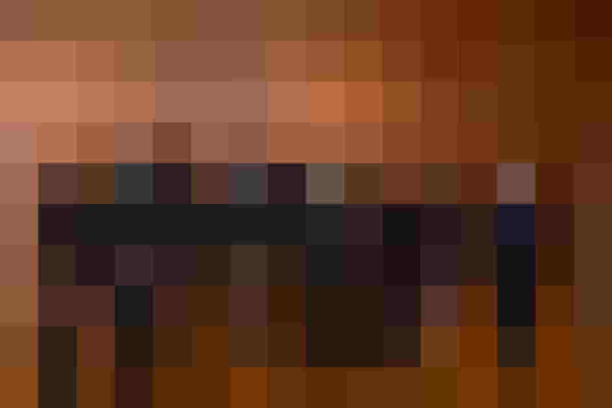 Acht Personen in formeller Kleidung vor Holzvertäfelung